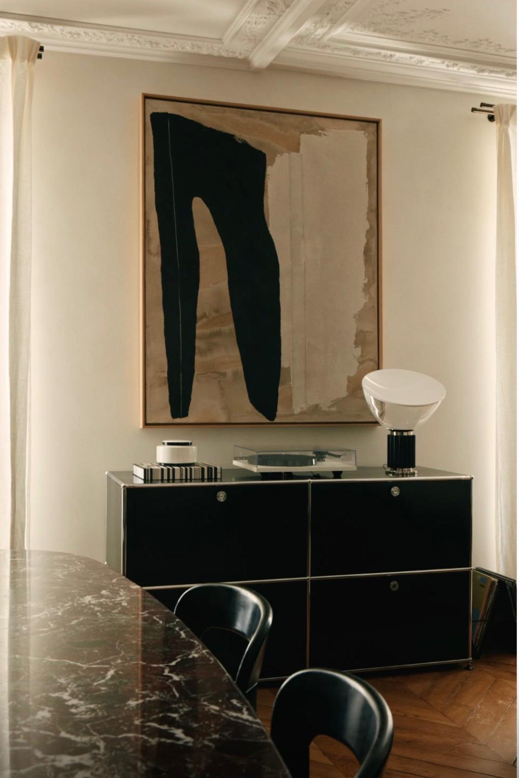 Salle à manger avec enfilade noire, œuvre contemporaine et lampe en verre opalin
