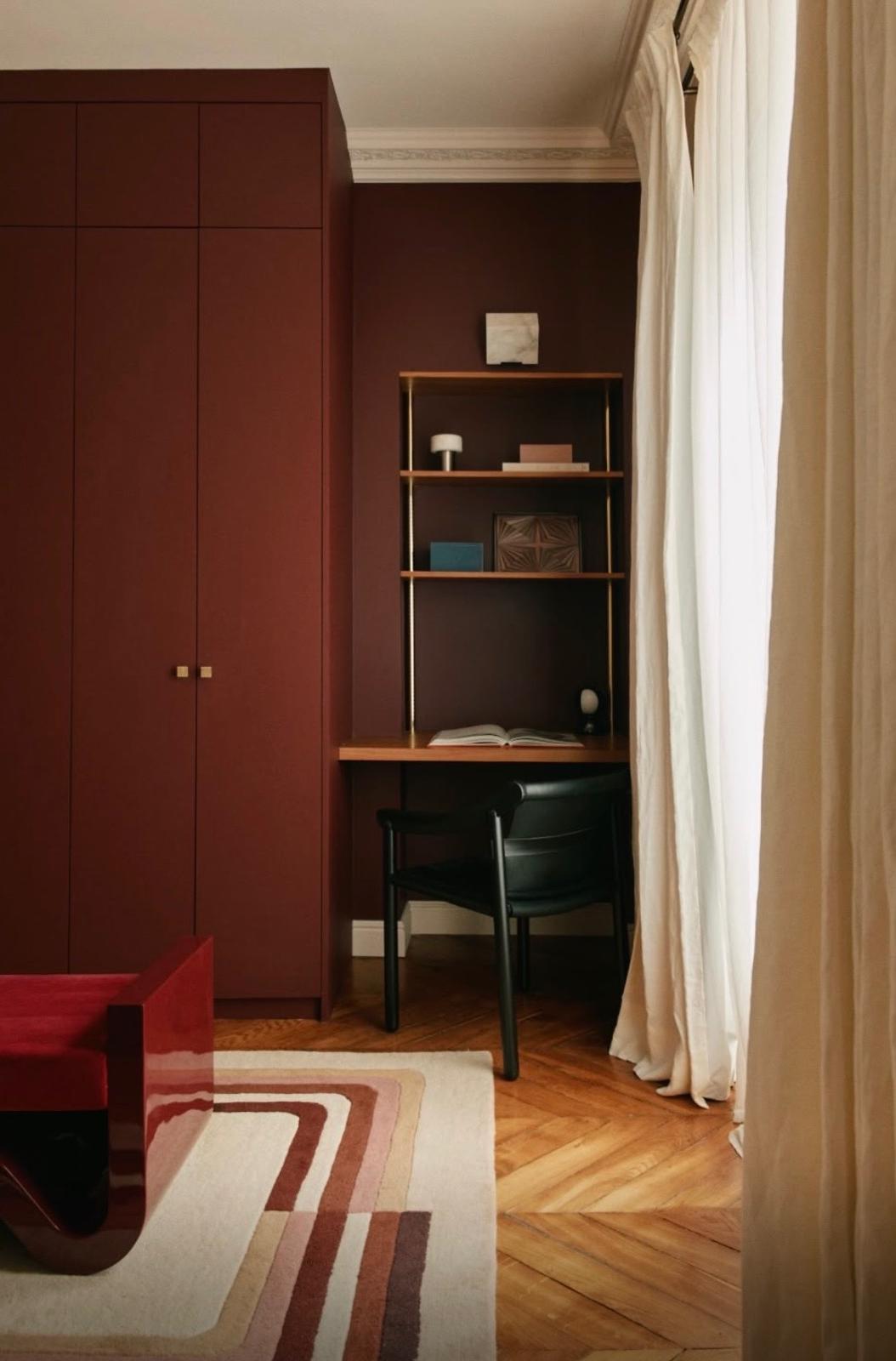 Bureau intégré dans un rangement laqué bordeaux avec étagères laiton et chaise noire