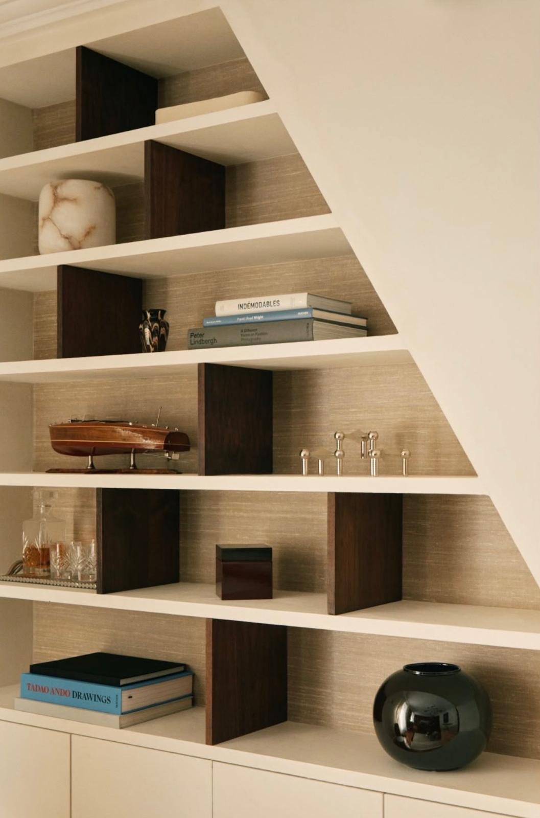 Espace professionnel conçu par Studio VH : bibliothèque sur mesure sous escalier, matières bois et plâtre